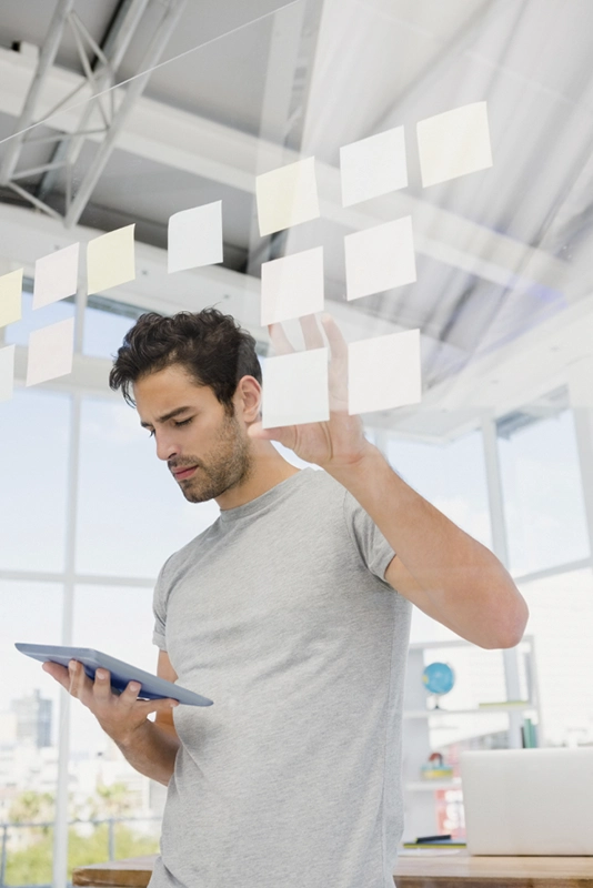 hombre con tablet y posit en un cristal